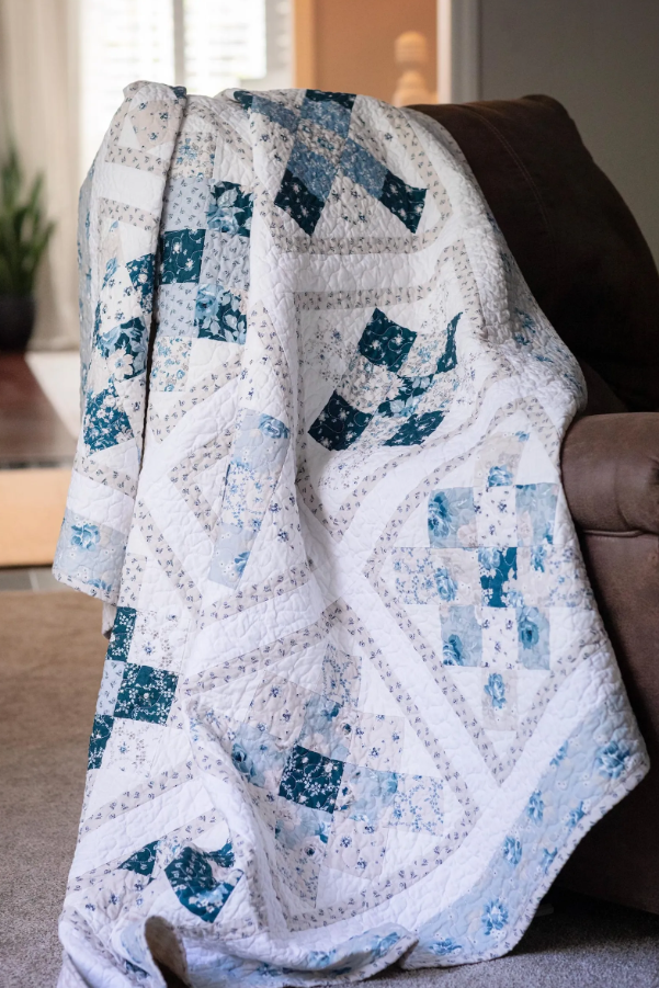 Classic Block quilt pattern with blue and white patchwork draped over a couch in a living room