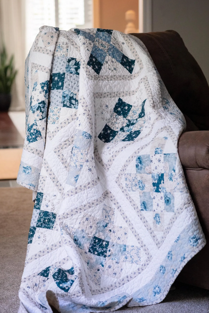 Classic Block quilt pattern with blue and white patchwork draped over a couch in a living room