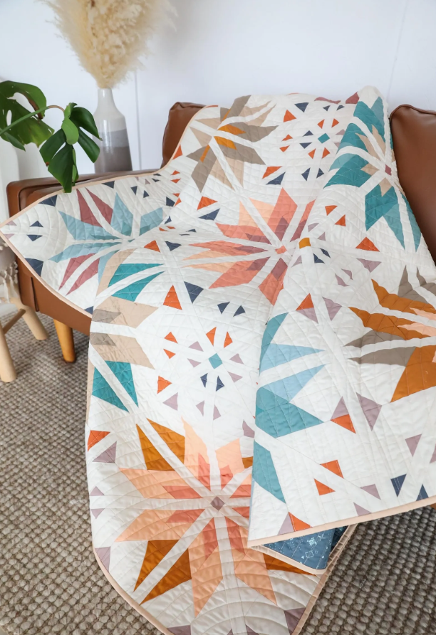 Sweet Creek Quilt Pattern PDF – handmade star quilt folded on leather armchair, cozy living room styling