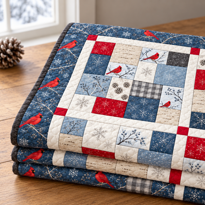 Folded winter cardinal quilt on a wooden table with a pinecone