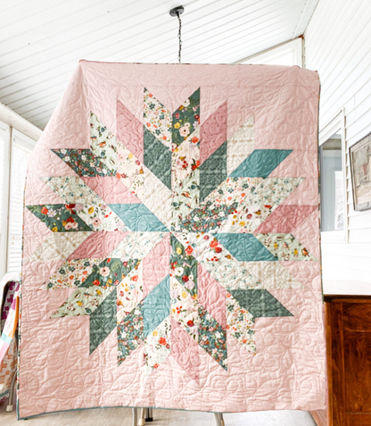 Floral Star quilt hanging display showing real finished quilt – pink and teal modern star patchwork PDF pattern for beginners