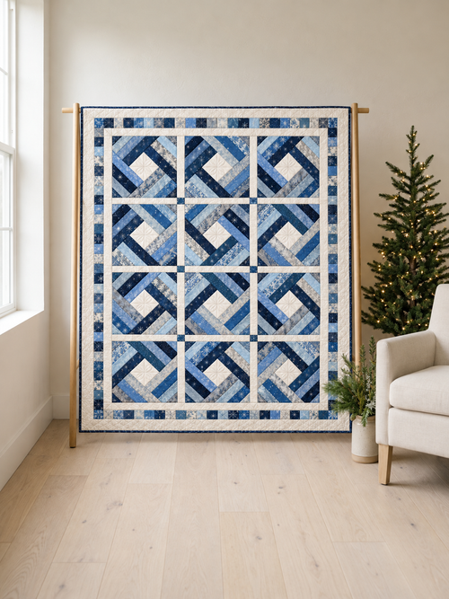Frostlight Diamond blue and ivory quilt on an oak stand beside a Christmas tree