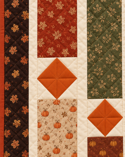 Close-up of quilted orange accent diamonds, cream sashing and pumpkin and leaf print rectangles