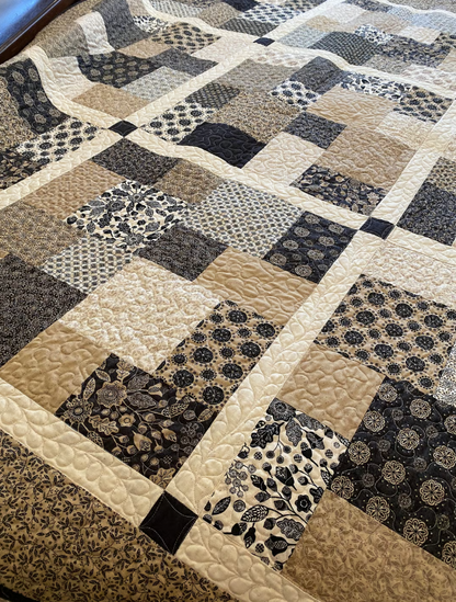 Layer Cake Toss Quilt detail shot – close-up of black, beige, and cream patchwork squares with quilting stitches
