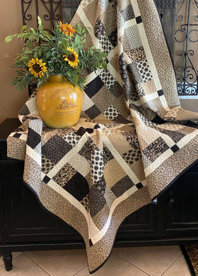 Layer Cake Toss Quilt draped over furniture – handmade patchwork throw quilt in brown and cream batik prints