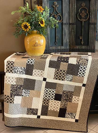 Layer Cake Toss Quilt displayed on table – beginner quilt PDF pattern in mixed batik scraps, home decor styling