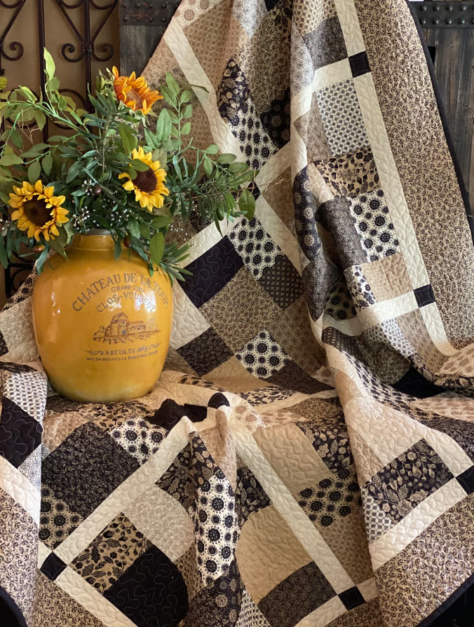 Layer Cake Toss Quilt styled with sunflower vase – patchwork quilt PDF pattern in dark and light batik fabrics