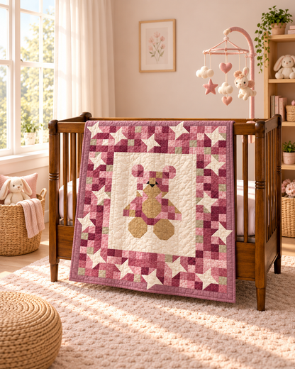 Teddy bear baby quilt in blush pinks over the side of a crib, with a baby mobile and soft toys in the room