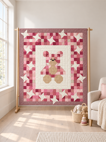 Pink teddy bear and stars baby quilt hanging on a wooden quilt stand in a bright nursery