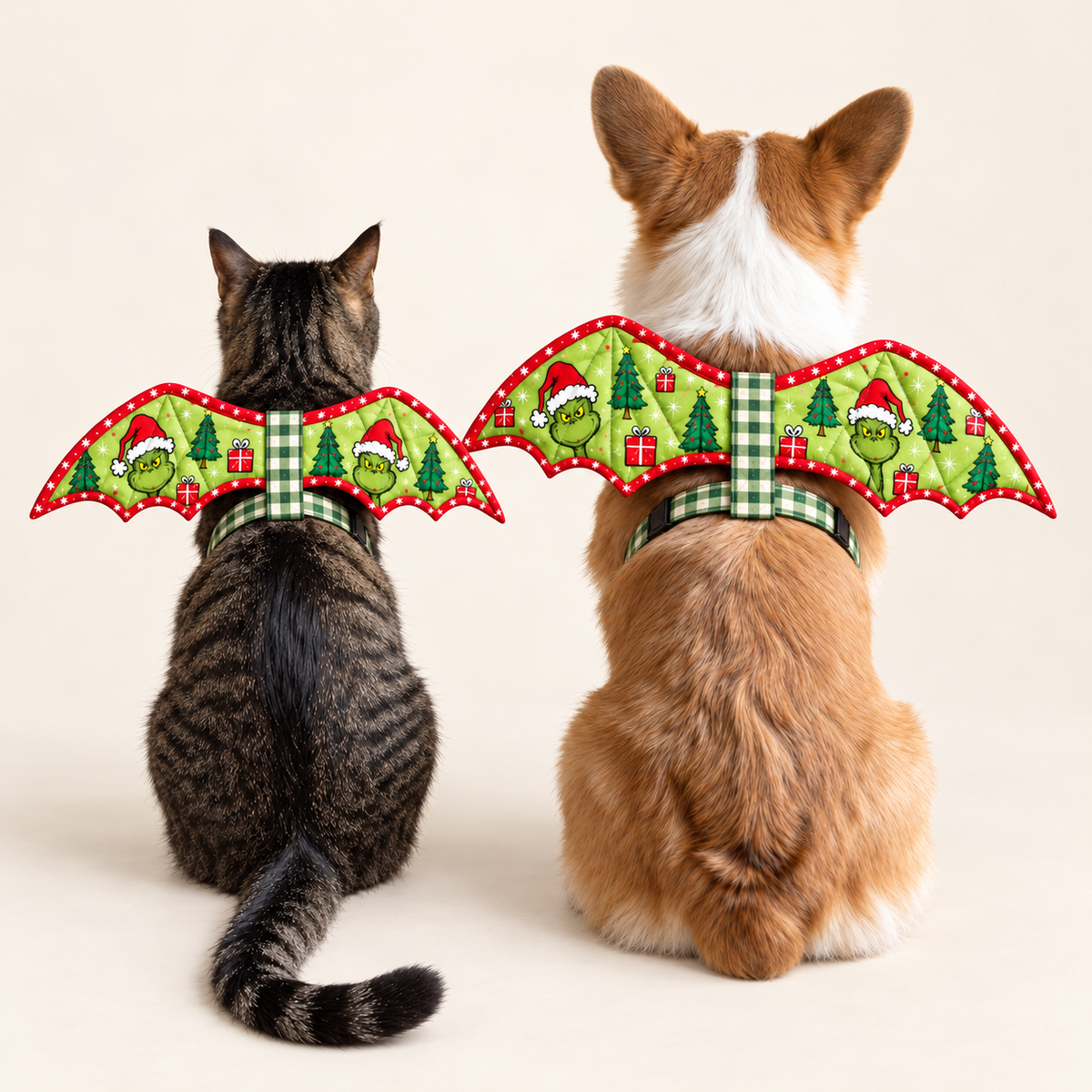 Cat and corgi wearing matching green Christmas bat-wing costumes on a clean ivory background. AI-generated fabric-styling illustration.