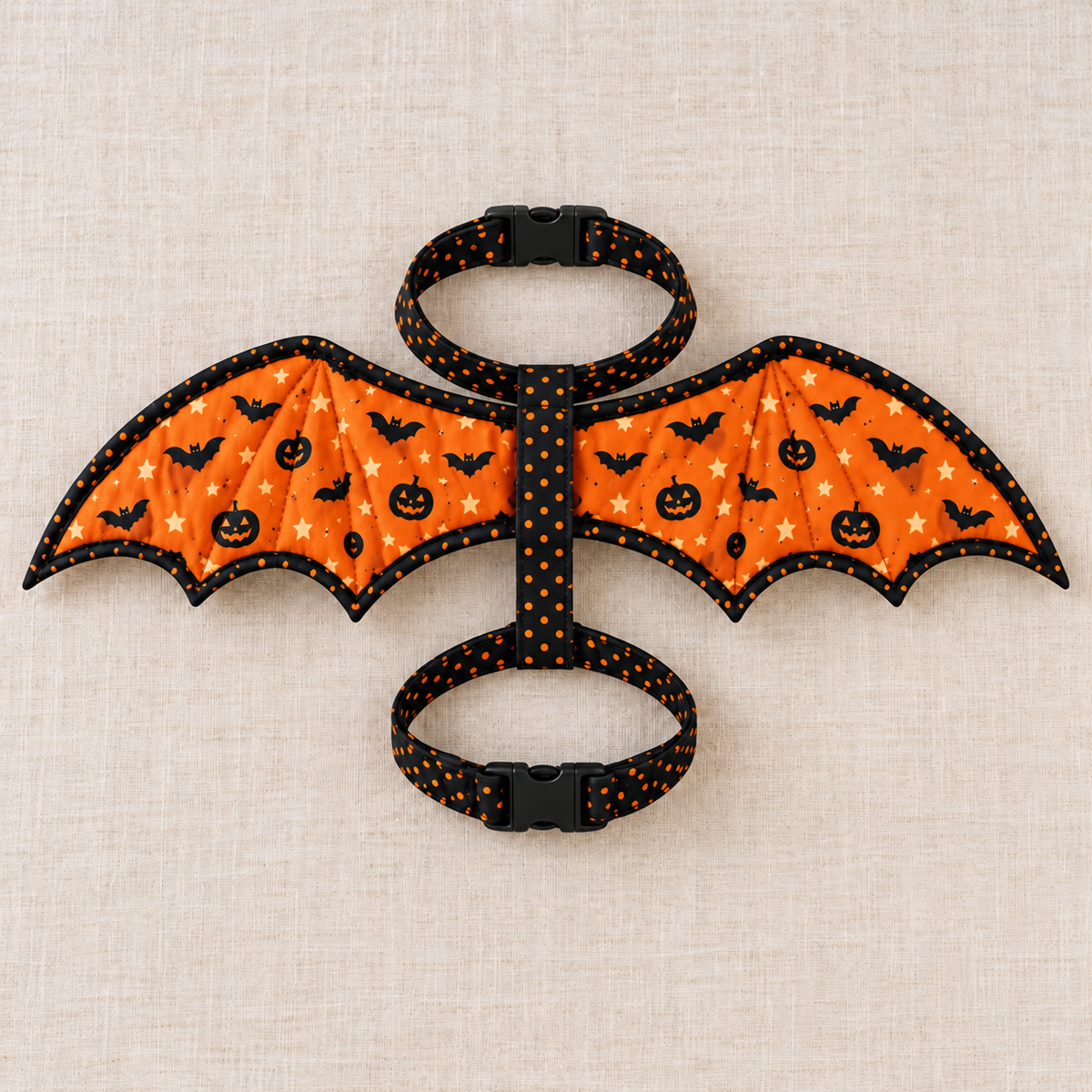 Flat lay of the complete Pumpkin Flight fabric bat wing harness showing neck and chest strap loops and black buckles