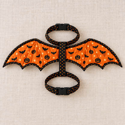 Flat lay of the complete Pumpkin Flight fabric bat wing harness showing neck and chest strap loops and black buckles