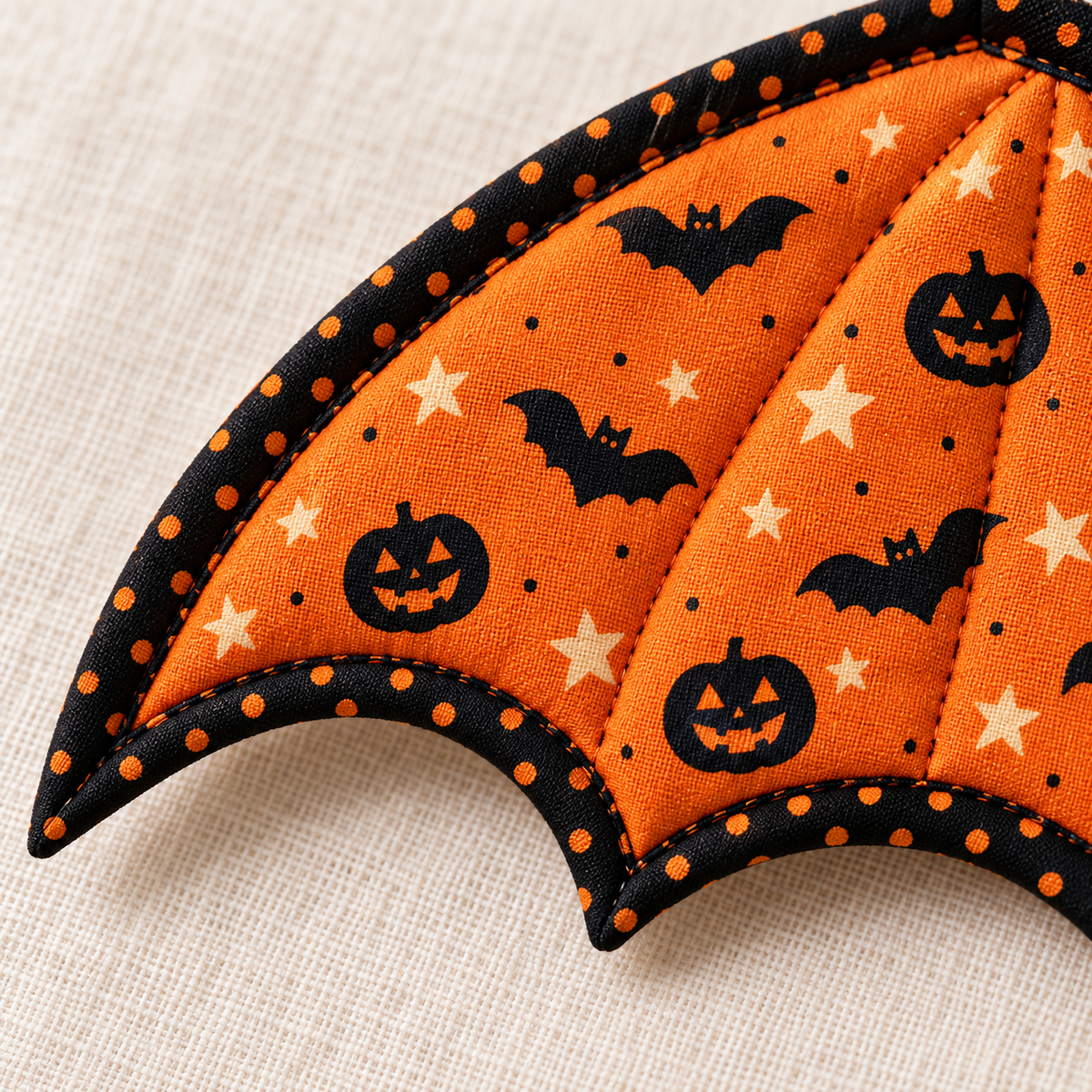 Close-up of orange bat and pumpkin print cotton, quilting and black orange-dot binding on a Pumpkin Flight wing