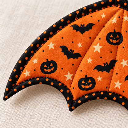 Close-up of orange bat and pumpkin print cotton, quilting and black orange-dot binding on a Pumpkin Flight wing