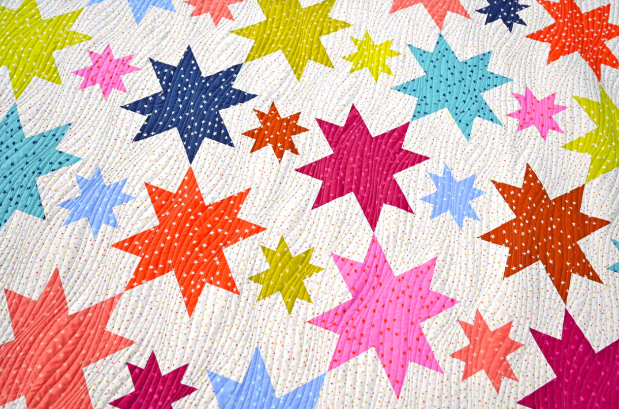 Close-up of Starburst quilt showing colourful bold star blocks on white background – modern star patchwork quilt PDF pattern