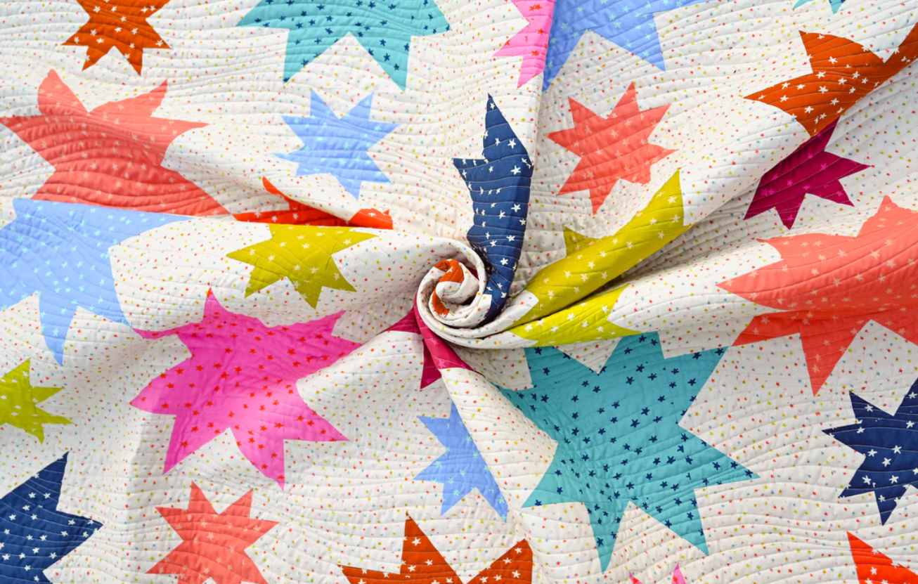 Starburst quilt fabric detail showing colourful bold stars swirled together – rainbow star patchwork quilt PDF pattern for all skill levels